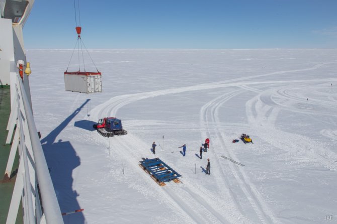 On the fast ice, dry content containers are loaded onto Pistenbully sledges, to be towed to Neumayer station.