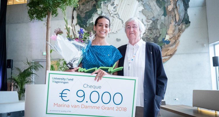 Julia Samsom, winnares van de Marina van Damme beurs, houdt haar cheque op naast Mevrouw van Damme.