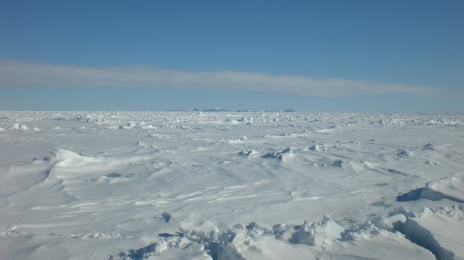 De Arctische Oceaan bedekt met zee-ijs. Op de achtergrond zijn net de toppen van Spitsbergen te zien.