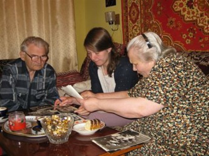 Yuliya Hilevych bekijkt fotoboeken bij een echtpaar in Lviv