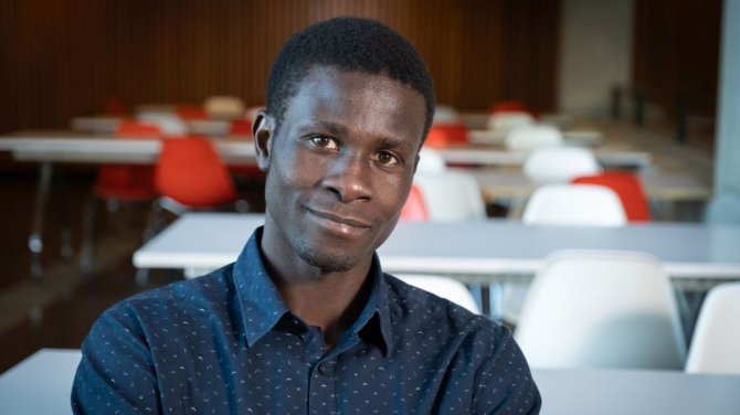 Alex Ogelo sits in a lecture room