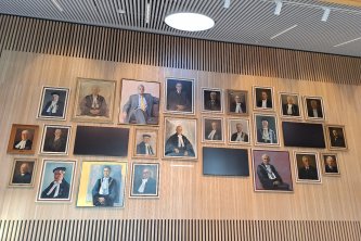 25 portrait paintings and 3 wide screens displayed on the wall in Omnia