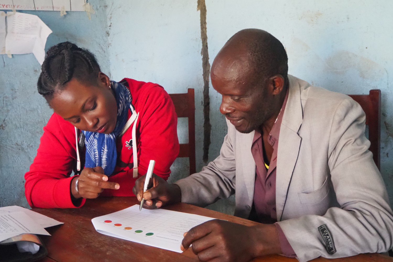 A research assistant conducts a questionnaire with an extension agent on the beta version of a smartphone application for diagnosing and monitoring wilt disease and providing information on agronomic practices to banana farmers.