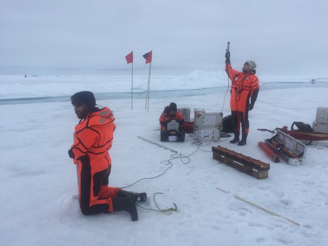 Team Iceflux performing light transmission measurements using an L-arm. For comparison a light sensor is held up to the sky to measure the amount of light that is available (Photo Fokje Schaafsma).