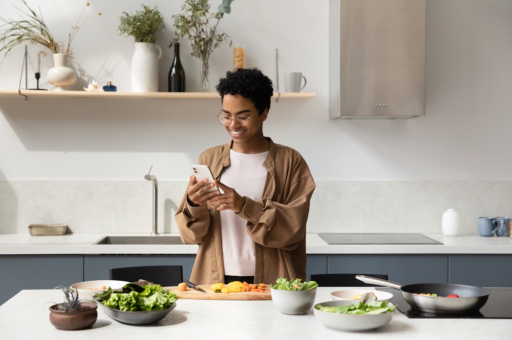 Woman in kitchen looking at phone