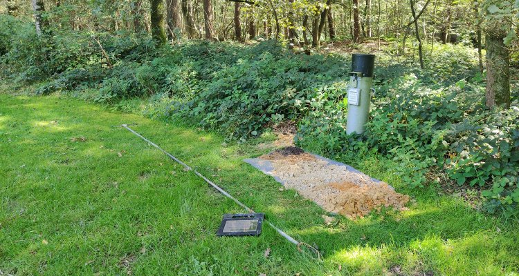 Grondboring voor meting van de grondwaterspiegeldiepte bij een grondwaterpeilbuis.