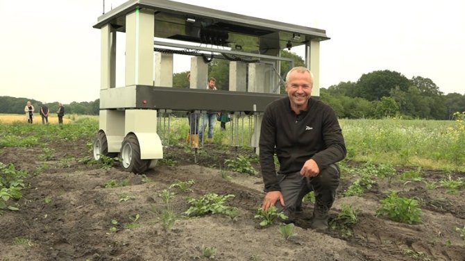 Farmer Arjen van Buuren in front of a robot at the Velhorst estate.