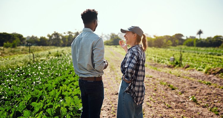 Two people on farmland. One is visibly laughing, the other is looking away from the camera.