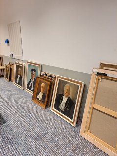 Several removed portrait paintings standing against a wall on the floor