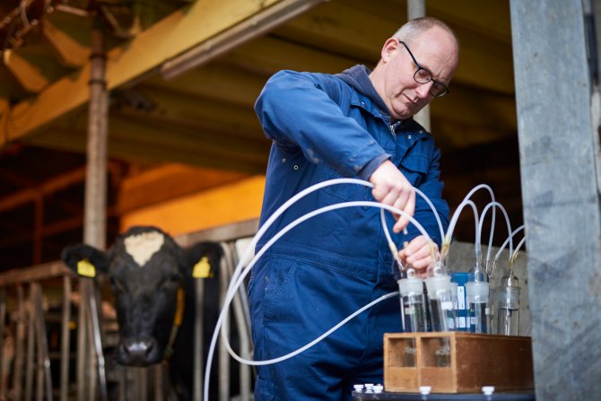 Onderzoeker Hendrik Jan van Dooren sluit de flesjes aan waarmee ammoniak gemeten wordt  
